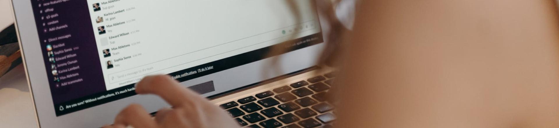Employee using a laptop and messaging platform while coordinating a 1-2-4-All discussion activity.